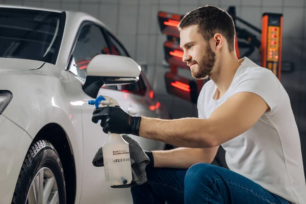 Glücklicher Kerl, der in der Autowerkstatt mit einem Spray arbeitet — Stockfoto