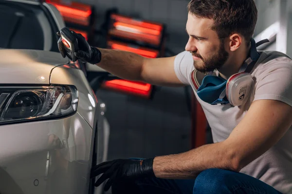 Aantrekkelijke monteur op zoek naar eventuele schade van een voertuig — Stockfoto