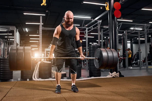 Sportiv kroppsbyggare med skivstång i gymmet — Stockfoto