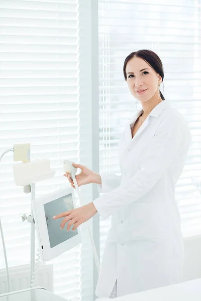 Portrét usmívajícího se kosmetologa v bílé lékařské neformě s přístrojem LPG — Stock fotografie