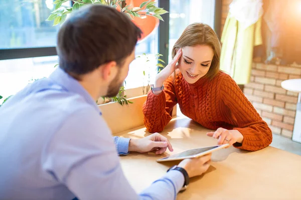 Güzel bir çift tabletle kafede oturuyor.