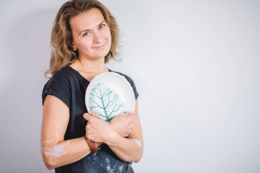 Kadın tezgahı bitmiş çatal bıçaklarla, gülümseyen seramikçi işyeri fırınlanmış fincanlarla