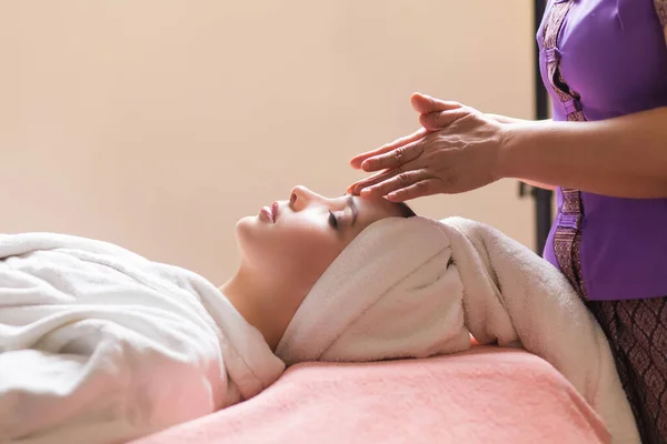 Vrouw liggen met gesloten ogen en het hebben van gezicht of hoofd massage in spa — Stockfoto