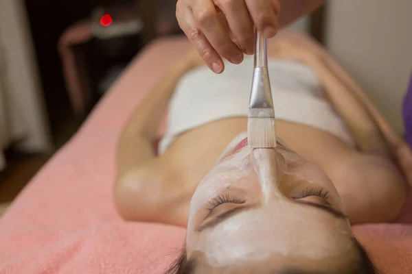 Kadın yalan söylüyor ve kozmetik uzmanı kaplıcada yüz maskesi takıyor. — Stok fotoğraf