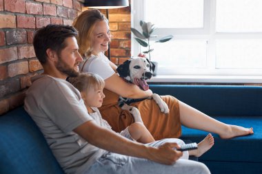 Çekici, mutlu bir aile ve oturma odasında köpek televizyonu var.