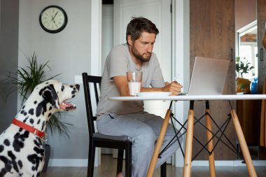 Karantina sırasında evde dizüstü bilgisayarda çalışan yakışıklı bir adam.