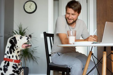 Karantina sırasında evde dizüstü bilgisayarda çalışan yakışıklı bir adam.