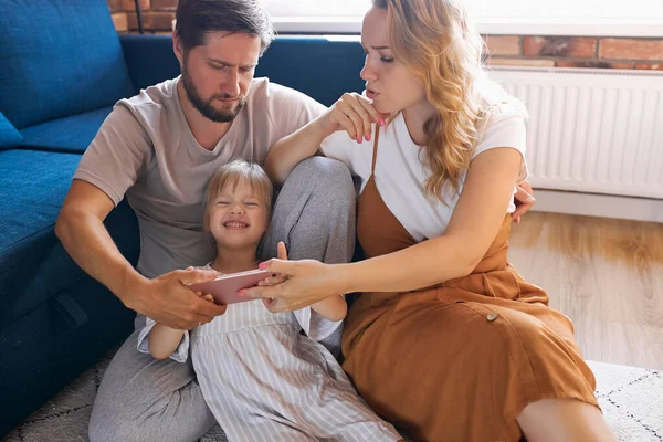 Feliz familia ver divertido vídeo en el teléfono móvil — Foto de Stock