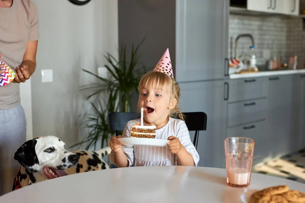 Malá krásná dívka sfoukne svíčky na dortu, narozeninová oslava — Stock fotografie