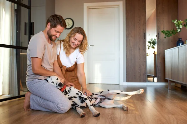 Casal brincando com cão de estimação em casa — Fotografia de Stock