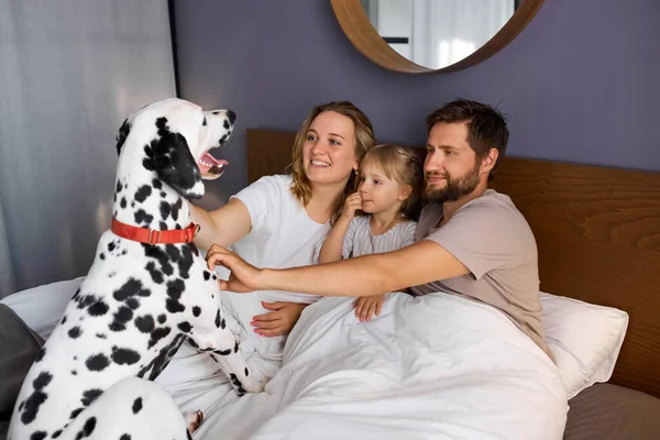 Retrato de jovem família caucasiana se divertindo com o cão em casa — Fotografia de Stock