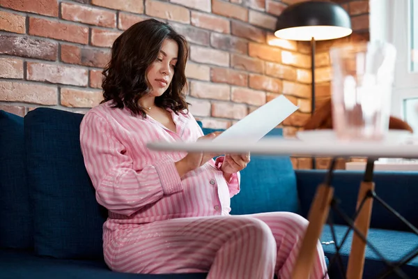 Zelfverzekerde zwangere vrouw verwachten baby, zitten lezen notities op papier — Stockfoto