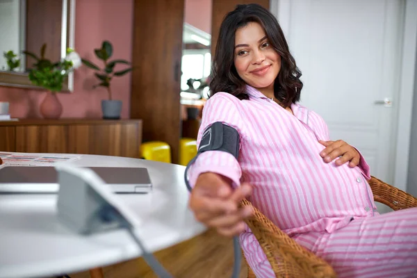 Wanita hamil mengukur tekanan darah dengan tonometer elektronik di rumah. — Stok Foto