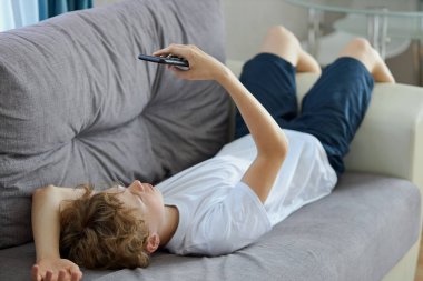 Genç kızıl saçlı çocuk cep telefonundan ilginç videolar izliyor.