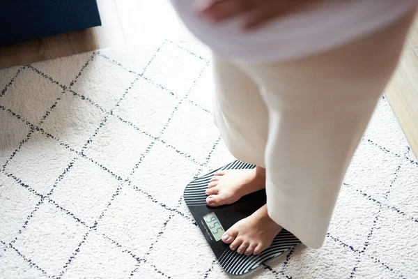 Беременная женщина проверяет свой вес дома — стоковое фото