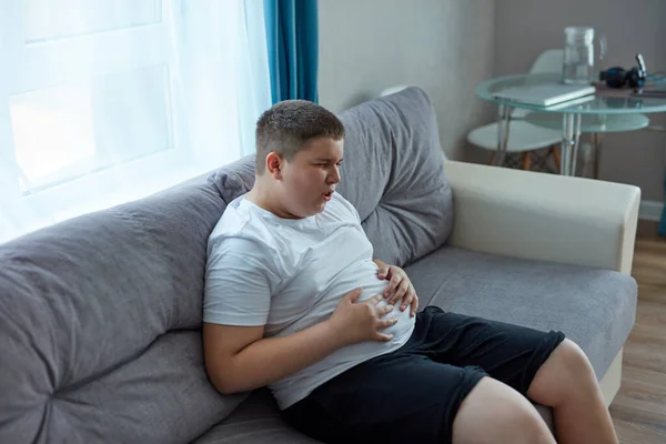 У мальчика вздутие живота после жирной еды — стоковое фото
