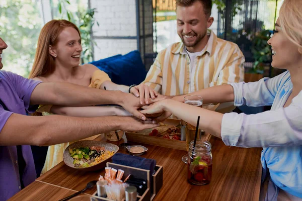 Кавказька група кращих друзів об'єднала руки, сидячи за столом кафе — стокове фото