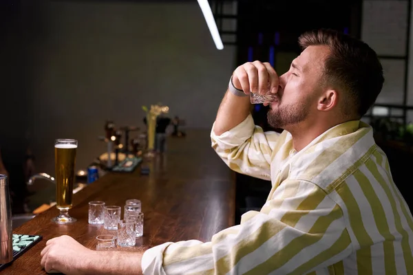 People, loneliness, alcohol concept. sad single young man drinking alcohol at bar or pub — Stock Photo, Image