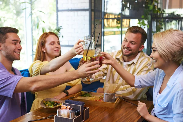 Grupo de amigos tintinean vasos con bebidas en la cafetería — Foto de Stock