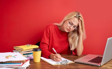 Ofis masasında oturan, aşırı çalışan, mutsuz ve hayal kırıklığına uğramış, stresli beyaz bir kadın.