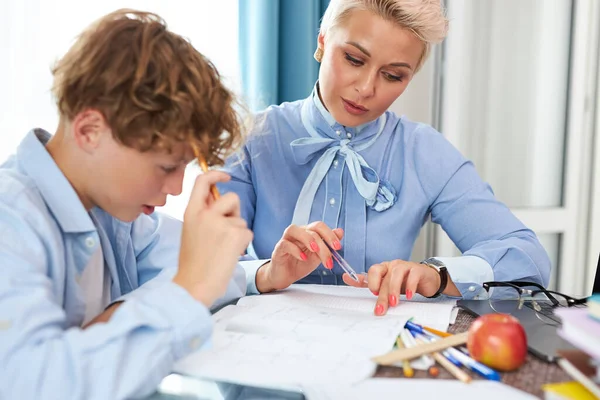 Joven profesora mujer ayudar adolescente chico a hacer tarea —  Fotos de Stock