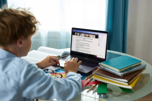 Skolpojke skriver rapport på laptop, gör läxor — Stockfoto