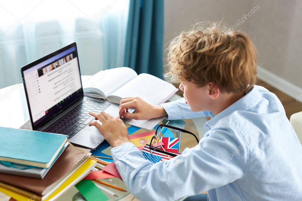 schoolboy prepares a presentation, writes a report, types on a laptop keyboard