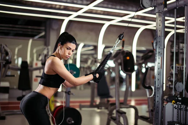 Vrouw doet oefening bij crossover machine in de sportschool — Stockfoto