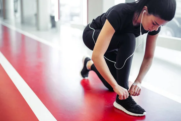 Жінка зав'язує шнурки у фітнес-центрі перед бігом на біговій доріжці — стокове фото