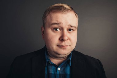 Kafkasyalı şişman adam kameraya bakıyor.