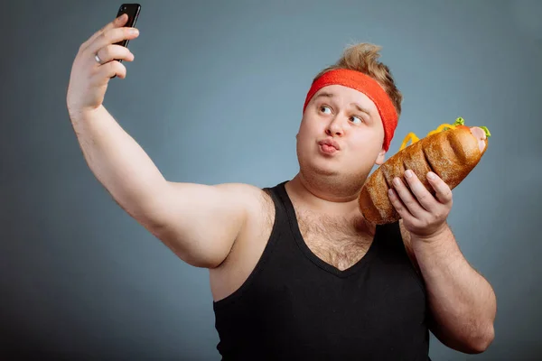 Grubas z kanapką w ręku robi selfie — Zdjęcie stockowe