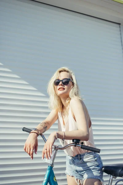 Mooi meisje met blond haar met fiets geïsoleerd op witte achtergrond. — Stockfoto