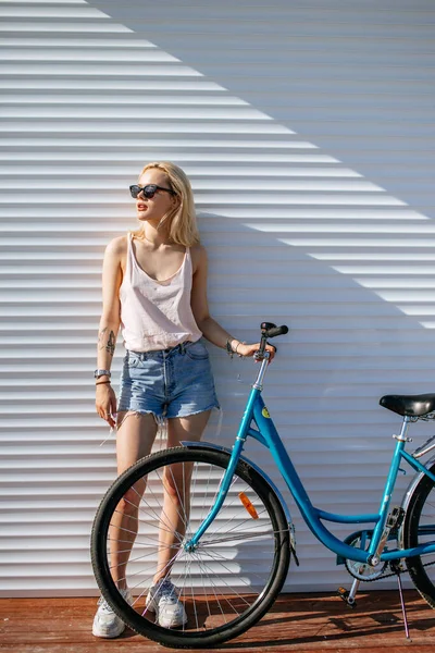 Mujer con el pelo rubio cerca de la bicicleta aislado sobre fondo blanco. —  Fotos de Stock