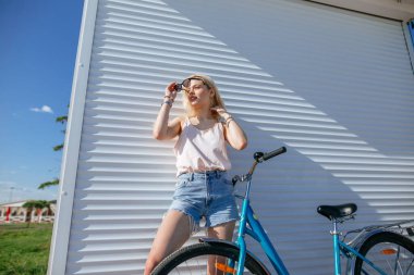 Sarışın, bisiklet süren güzel bir kız beyaz arka planda izole edilmiş..