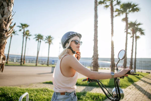 Menina jovem usando capacete e óculos de proteção fica perto de bicicleta elétrica — Fotografia de Stock