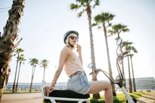 Menina jovem usando capacete e óculos de proteção fica perto de bicicleta elétrica — Fotografia de Stock