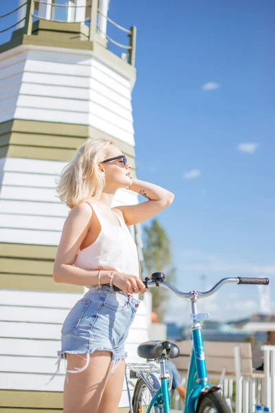 Kvinnan lutar sig mot cykeln när hon står nära observationsdäcket på stranden — Stockfoto