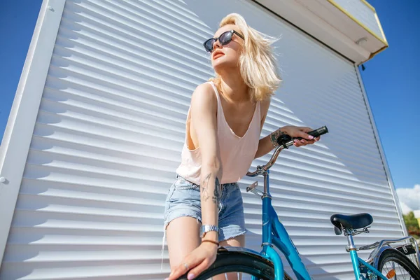 자전거 근처에서 금발 머리를 하고 있는 여자, 흰 배경에 따로 떨어져 있다. — 스톡 사진