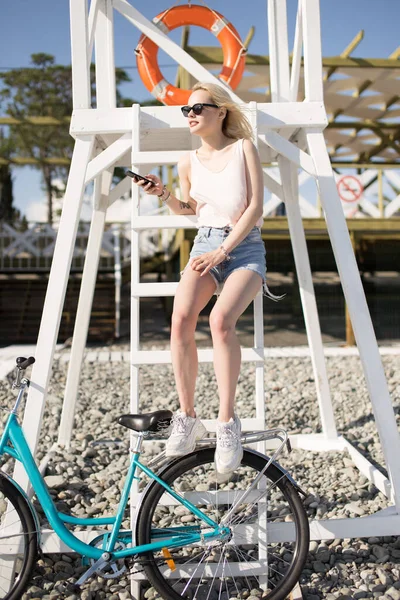 Mujer joven descansando después de ciclismo rápido en una playa de guijarros. Concepto de relajación —  Fotos de Stock