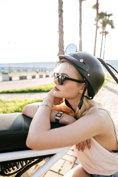 Chica joven con casco y gafas de protección se sienta cerca de la bicicleta eléctrica — Foto de Stock