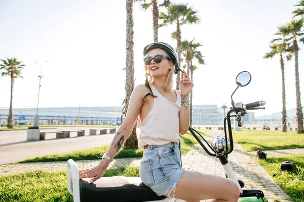 Молодая девушка в шлеме и защитных очках сидит рядом с электрическим велосипедом — стоковое фото