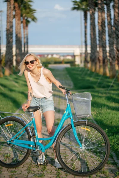 Mulher de pé perto de bicicleta alugada no parque. Verão e estilo de vida — Fotografia de Stock