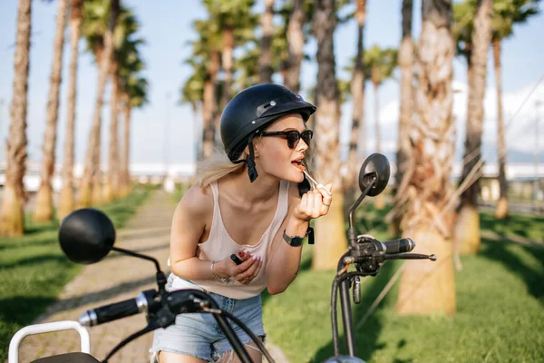 Mulher aplicando lipstic sentado na bicicleta elecrtic. — Fotografia de Stock