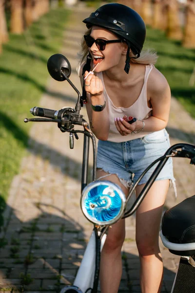 Mulher aplicando lipstic sentado na bicicleta elecrtic. — Fotografia de Stock