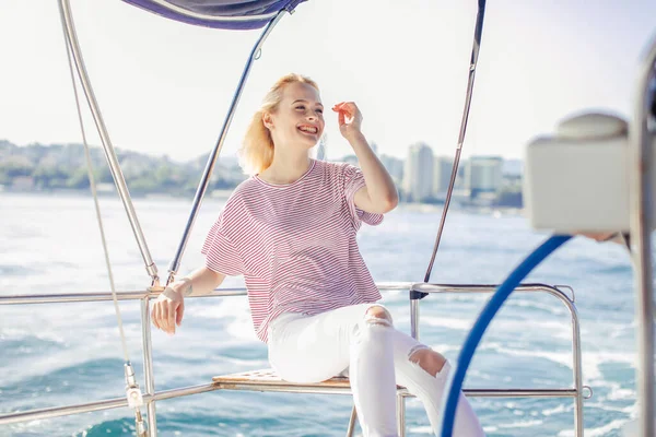 Donna su yacht bianco in tema nautico in mare aperto. Capelli biondi e vestiti blu. — Foto Stock