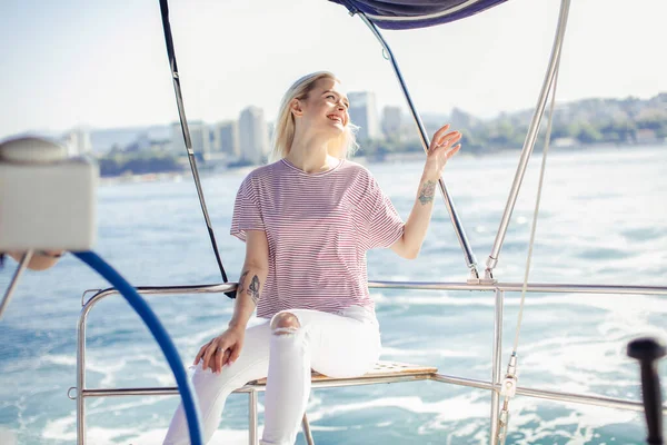 Žena na bílé jachtě v námořní téma na otevřeném moři. Blond vlasy a modré šaty. — Stock fotografie