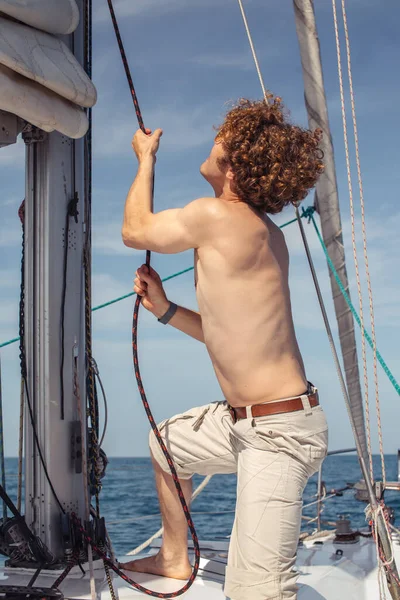 Vista basso angolo di giovane uomo barbuto in piedi sullo yacht naso — Foto Stock
