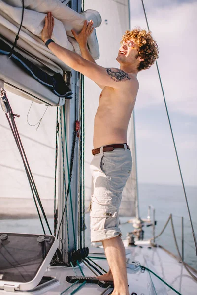 Hipster-Mann steht auf Geländer weißer Jacht vor ruhigem blauem Meer — Stockfoto