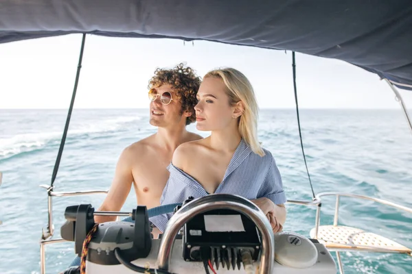 Açık denizde teknesiyle yelken açan çekici sarışın kadın.