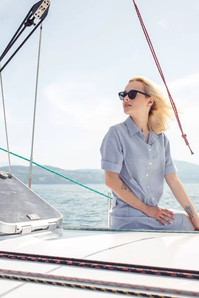 Žena na bílé jachtě v námořní téma na otevřeném moři. Blond vlasy a modré šaty. — Stock fotografie